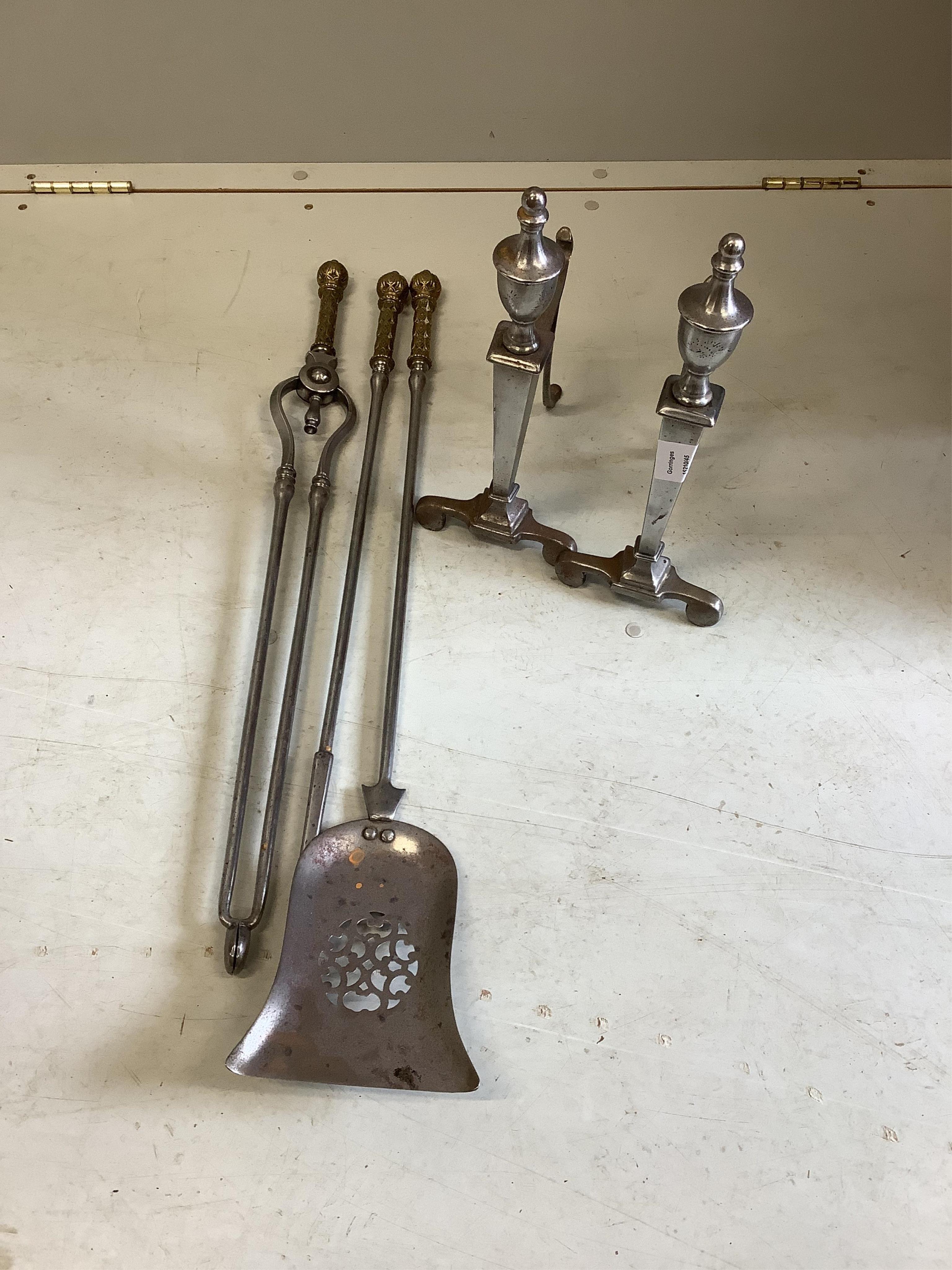 A set of three brass mounted polished steel fire implements and a pair of fire dogs. Condition - fair